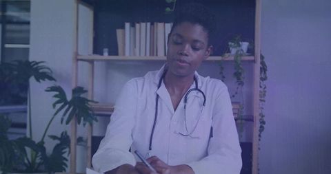 Female clinician writing notes wearing lab coat and stethoscope at calm organized desk