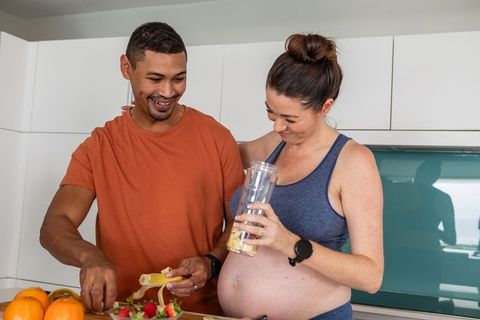 Pregnant Couple Making Smoothie Together in Modern Kitchen