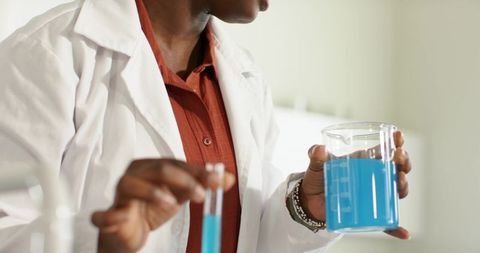 African-american scientist holding beaker and test tube with bright blue solution