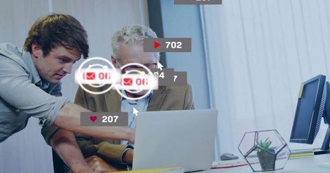 Younger professional mentoring senior colleague at laptop with digital engagement overlays