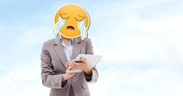 Businesswoman standing outdoors holding a tablet with crying emoji face. This humorous composition may be used to illustrate workplace stress, frustration with technology, or emotional expression in a business context. Ideal for blog posts, articles on emotions in the workplace, or content related to technology and communication.