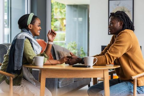 African american couple holding hands and talking over coffee at cozy home table