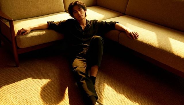 Reclining man on l-shaped sofa bathed in warm sunlight minimalist lounge portrait