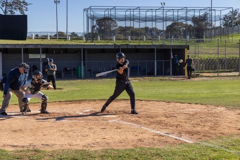 Community Baseball Batter Swinging at Home Plate with Umpire, Catcher and Dugout Action