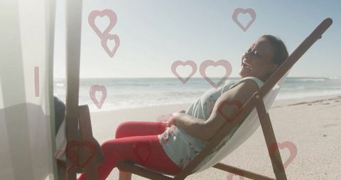 Woman enjoying relaxation on beach with overlay of heart graphics