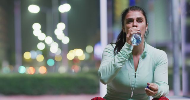 Fit woman drinking water while resting during night workout in city - Download Free Stock Images Pikwizard.com