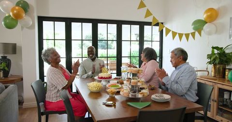 Senior friends celebrating birthday in casual home setting