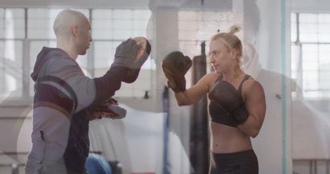 Female boxer punching focus mitts in gym training session