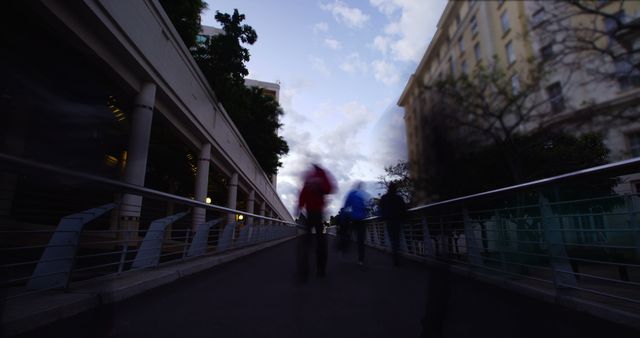 Blurred silhouettes walking through an urban street at dusk, characterized by motion and contemporary architecture. Suitable for articles on urban lifestyles, evening activities, and cityscapes, as well as enhancing urban planning resources or travel blogs.