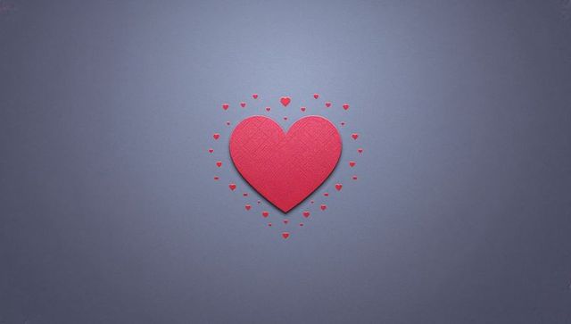 Textured red heart flatlay surrounded by tiny hearts on slate backdrop for valentine