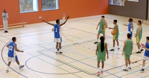 High School Boys Engaged in Competitive Basketball Game in Gymnasium