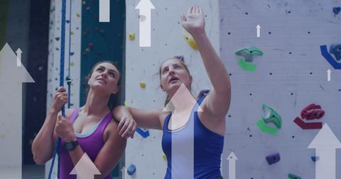 Women Engaged in Rock Climbing Indoors with Upward Arrows