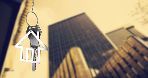 House Keychain Hanging Over Urban Skyscrapers in City