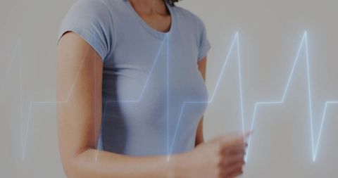 Mid adult woman moving arm with ecg waveform overlay for heart health and wearable tech