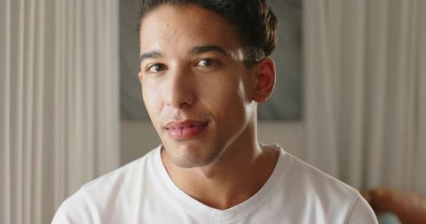Relaxed young man wearing white t-shirt looking into camera with hoop earring