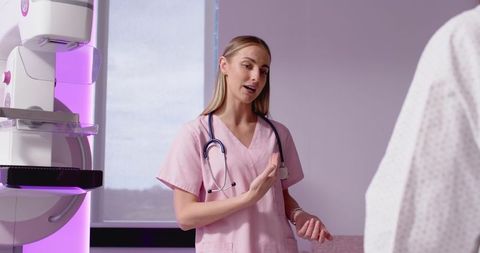 Mammography consultation with clinician in pink scrubs explaining breast imaging