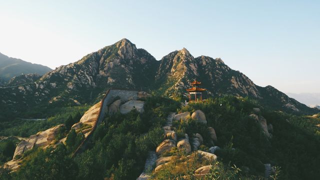 Beautiful mountain landscape featuring a traditional Chinese pavilion among rocky hills and lush greenery. Ideal for travel brochures, nature photography showcases, tourism websites, and promotional materials highlighting scenic destinations.