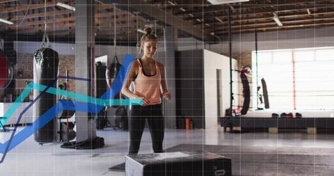 Athlete performing box jump in industrial boxing gym with punching bags and daylight