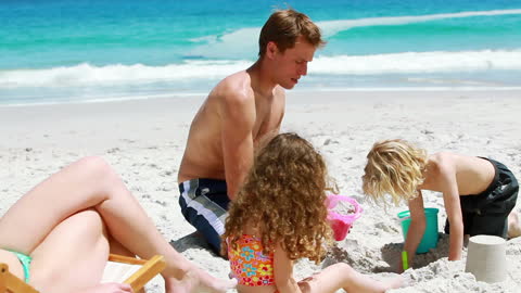 Father Enjoying Beach Day with Children Building Sandcastle