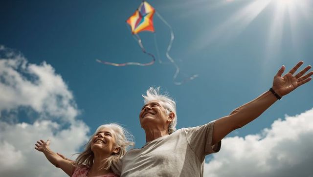 Senior couple enjoying sunny day flying colorful diamond kite under blue sky