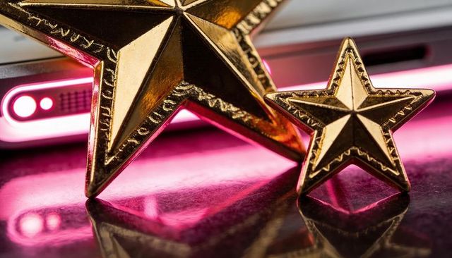 Gold stars reflecting on glossy surface while casting magenta smartphone glow