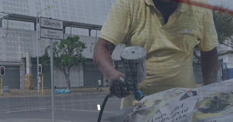 Urban worker spraying protective coating on object covered with newspaper in rainy street