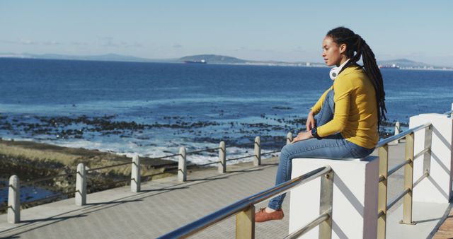 African american woman sitting on promenade by the sea - Download Free Stock Photos Pikwizard.com