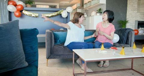 Senior Friends Preparing for Birthday Celebration in Living Room