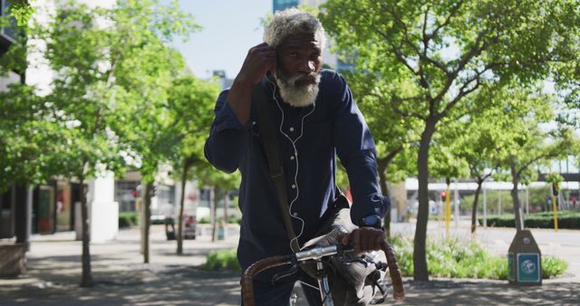 African american senior man sitting on bicycle wearing earphones on the road. active senior lifestyle living concept