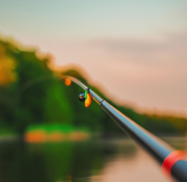 Image of close up of hand holding fishing rod against landscape. Fishing, hobby and leisure concept.