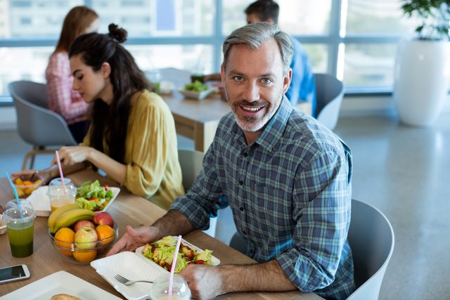 Smiling man having meal with his colleagues at office