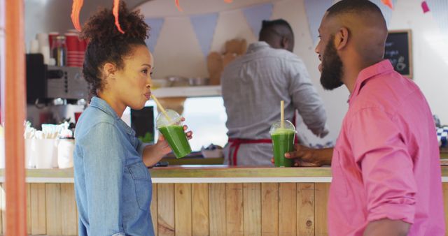 African american couple smiling while drinking smoothies at the food truck. food truck and street food concept