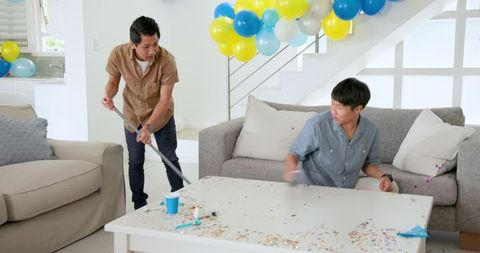 Asian Men Cleaning Living Room Post-Party