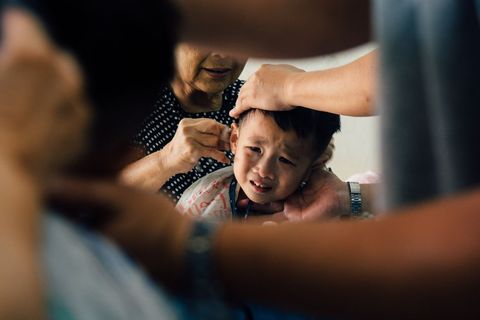 Child Undergoing Painful Ear Treatment with Medical Assistance