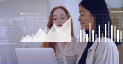 Female Colleagues Analyzing Data on Laptop with Graph Overlays in Modern Office
