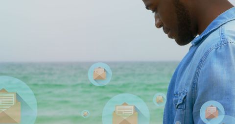 Man checking smartphone beachside with social media icons