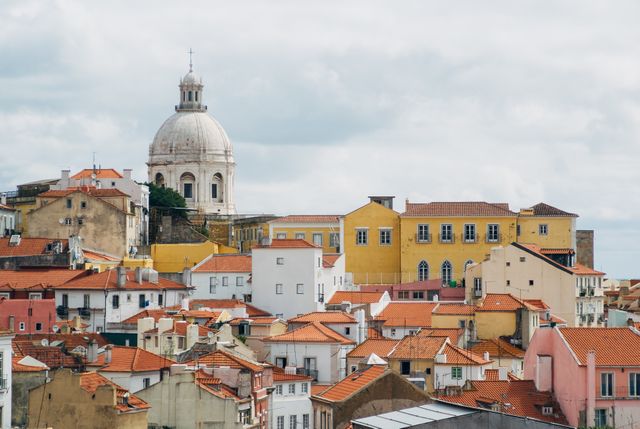 Photo features Lisbon's cityscape with iconic red-tiled rooftops and a prominent historical dome in the background. Ideal for travel blogs, digital tourism brochures, historical architecture articles, and cultural exploration themes.
