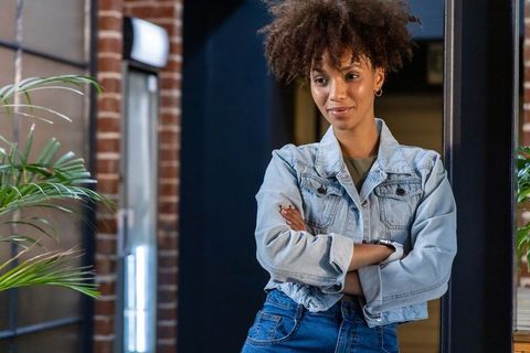 Confident african american woman leaning with arms crossed in modern coworking studio