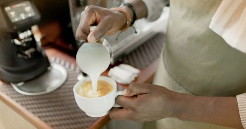 Barista skillfully creating latte art in a cozy cafeteria atmosphere