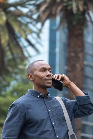 African american businessman talking on smartphone outside modern office tower