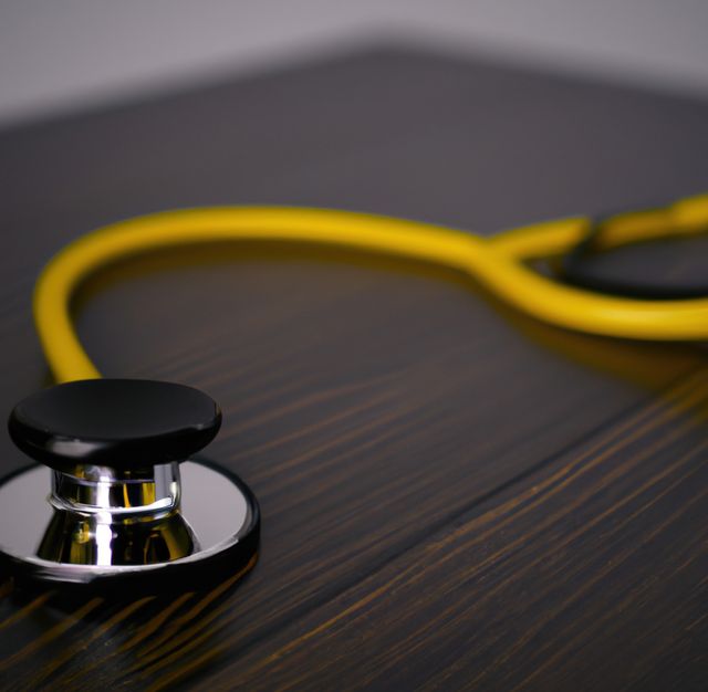 Image of close up with detail of yellow stethoscope on wooden background. Medicine, doctors and healthcare services concept.