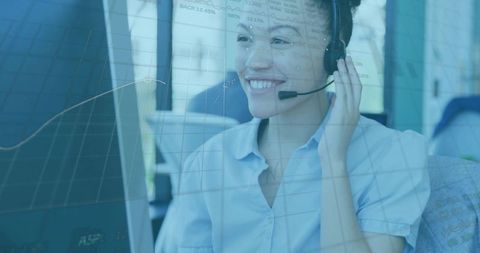 Smiling call center agent adjusting headset with analytics overlay on desktop monitor