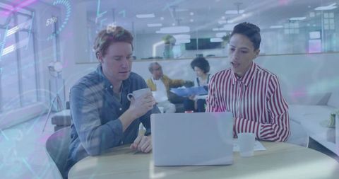 Professionals collaborating over laptop with HUD overlay in modern workspace