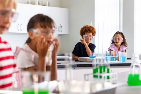 Elementary students conducting colorful chemistry experiment in bright modern lab