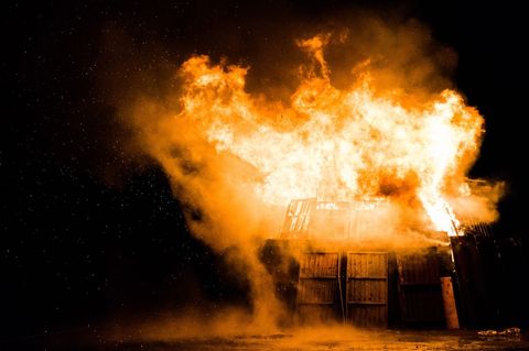 Wooden structure burning at night with intense flames and flying sparks