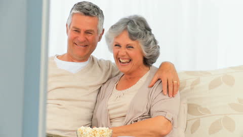 Happy Senior Couple Enjoying Popcorn Together