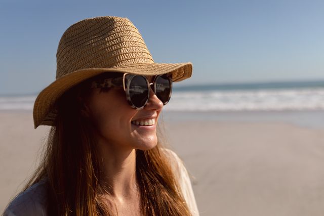 Happy woman in sunglasses and hat relaxing on the beach