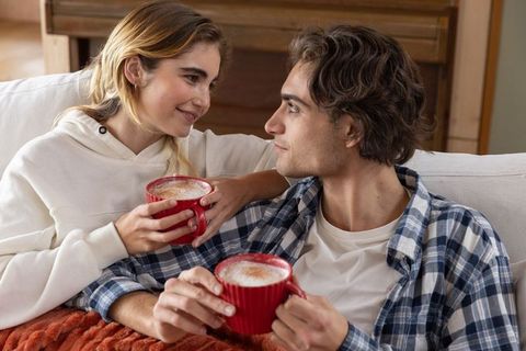 Young Couple Enjoying Warm Drinks on Cozy Couch