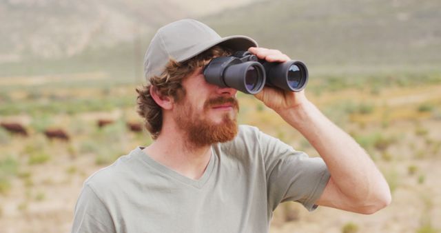 Bearded caucasian male survivalist looking to distance with binoculars in wilderness. exploration, travel and adventure, survivalist in nature.