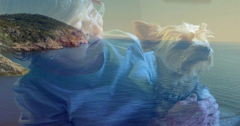 Senior woman holding terrier with coastal seascape double-exposure conveying companionship